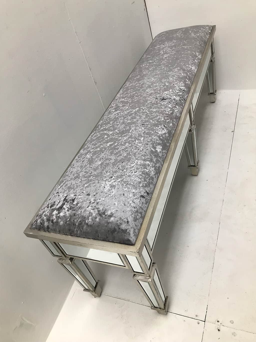Charleston Mirrored extra long stool with all bevelled mirror panels, upholstered in a silver crushed velvet fabric, supported on 6 legs, wood and mirror and cloth, antiqued silver finish.