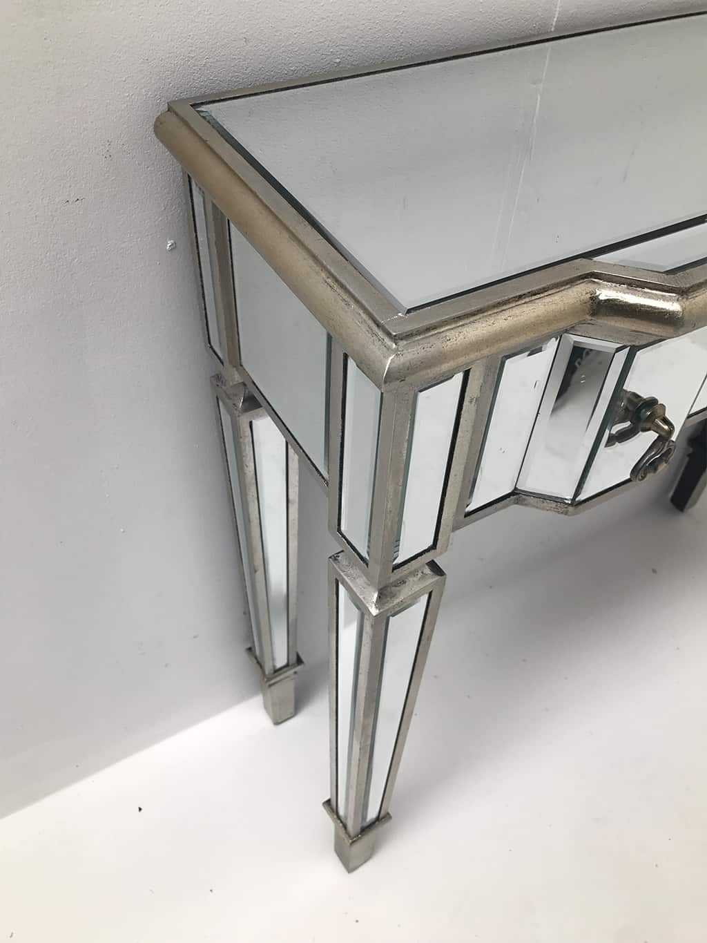 mirrored console table with 3 drawers, silver wood edging, glass top, tapered legs and drop Ring brass pulls